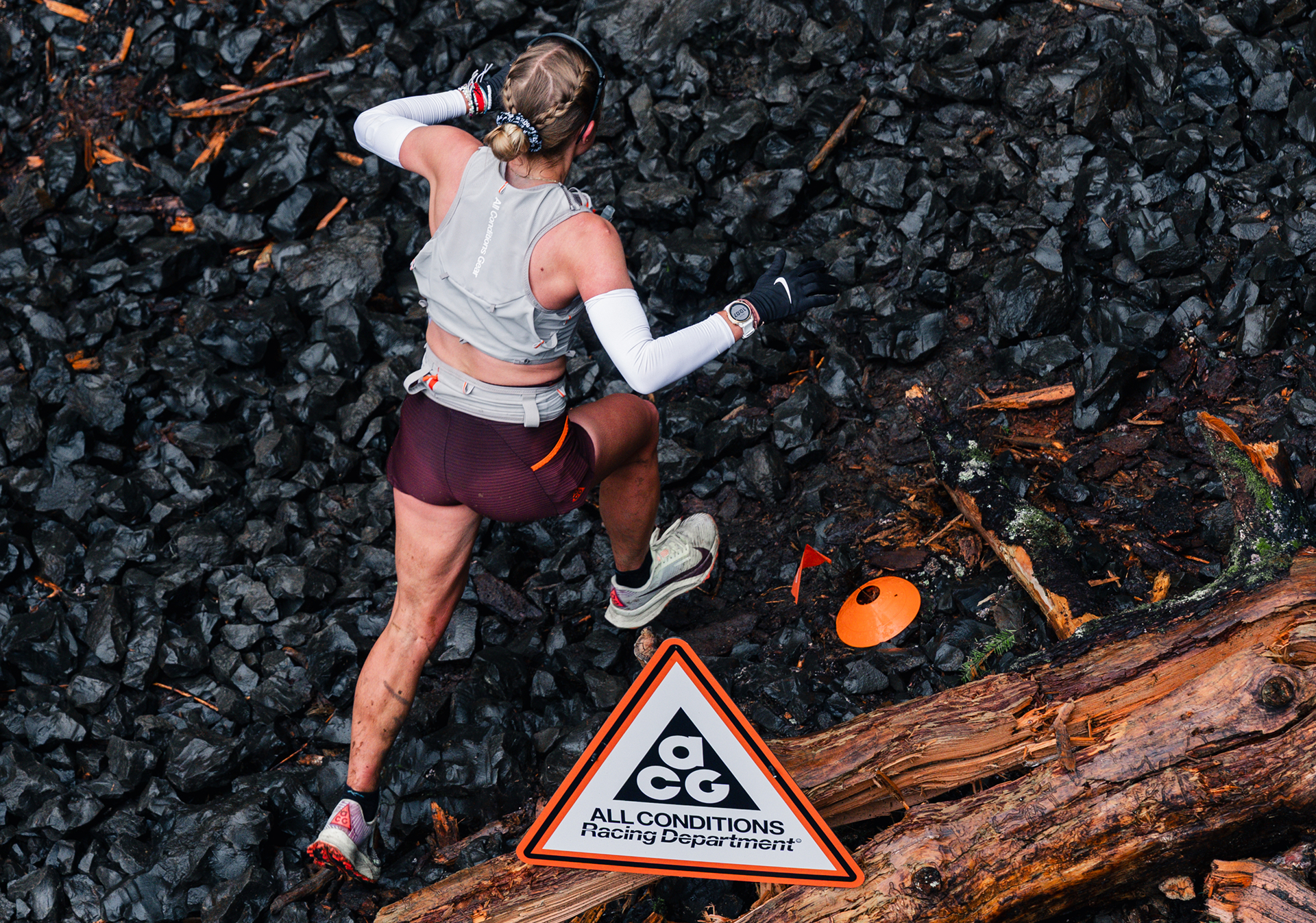 Image of a runner travelling up a rocky trail and past an All Conditions Racing Department sign.